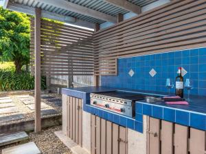 a kitchen with a stove and a blue tile wall at Akarana Beach House by Jervis Bay Rentals in Vincentia