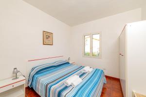 a white bedroom with a bed and a window at Residence Arcobaleno in San Teodoro