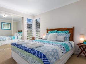 a bedroom with a large bed with towels on it at Akarana Beach House by Jervis Bay Rentals in Vincentia