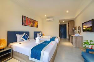 a bedroom with two beds and a television in a room at Hoi An Aurora Riverside Hotel and Spa in Hoi An