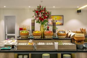 a buffet with bowls of food and a vase of flowers at Hoi An Aurora Riverside Hotel and Spa in Hoi An +78 photos