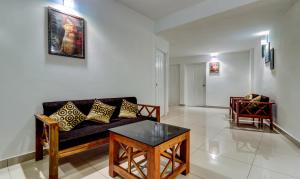 uma sala de estar com um sofá e uma mesa em Itsy By Treebo - Dew Dreams em Cochin