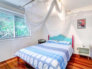 a bedroom with a blue and white bed and a window at The Shack in Seal Rocks
