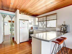 a kitchen with white appliances and a wooden ceiling at The Shack in Seal Rocks