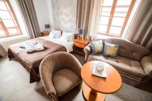 インドルジフーフ・フラデツにあるPenzion Pod Zamkemのベッド、ソファ、テーブルが備わるホテルルームです。