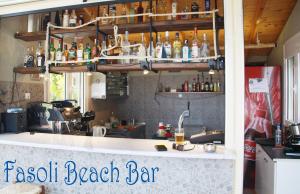 een strandbar met een bar met flessen aan de muur bij Fasoli Studios in Paralia Panteleimonos