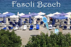 een stel stoelen en parasols op een strand bij Fasoli Studios in Paralia Panteleimonos