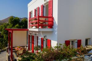 Edificio blanco con persianas rojas y balcón en Sea View Villa, en Megas Gialos - Nites