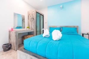 a blue bed with two white towels on it at Barista Hotel in Uttaradit