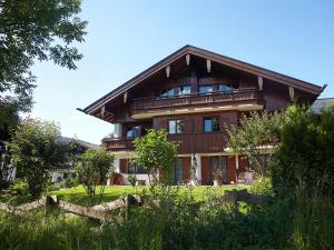 ein großes Holzhaus mit einem Zaun davor in der Unterkunft Ferienwohnungen Schwendinger in Oberstdorf