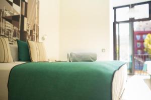 Cama verde en habitación con ventana en Limonaia, en Barcelona
