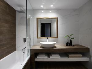 a bathroom with a sink and a mirror and a tub at Pelagos Suites Hotel & Spa in Kos