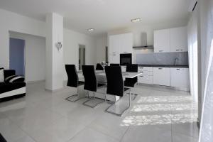 a white kitchen with a table and black chairs at Apartments Lola in Novalja