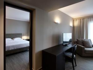 a hotel room with a bed and a desk with a computer at Pelagos Suites Hotel & Spa in Kos