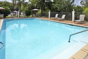 a large blue swimming pool with two lawn chairs at Holiday Inn Express Breaux Bridge, an IHG Hotel in Henderson