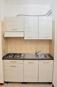 uma cozinha com armários brancos e um lavatório em Condominio Tonin B em Bibione