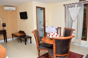 ein Wohnzimmer mit einem Tisch, Stühlen und einem TV in der Unterkunft Hotel Mataram 2 Malioboro in Yogyakarta