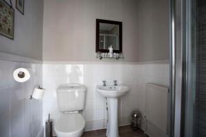 a white bathroom with a toilet and a sink at Dunstan House in Burnham on Sea