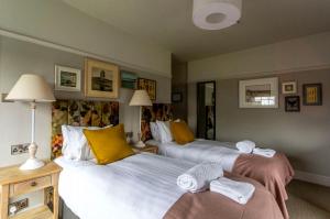 two beds in a hotel room with towels on them at Dunstan House in Burnham on Sea