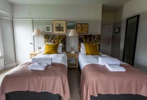 two beds in a hotel room with towels on them at Dunstan House in Burnham on Sea