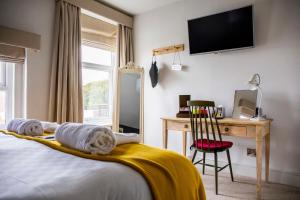 a bedroom with a bed and a desk and a television at Dunstan House in Burnham on Sea