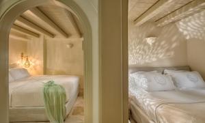 a bedroom with two beds and an arched doorway at THE A COLLECTION by K&K in Oia