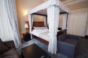 a bedroom with a canopy bed and a couch at Palmerston Suites in Edinburgh