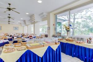 un salón de banquetes con dos mesas con comida. en Hotel Astoria, en Misano Adriatico