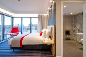 Una habitación de hotel con una cama y una silla roja. en Holiday Inn Express London-Ealing by IHG, en Londres 41 fotos más
