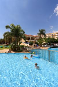 a swimming pool with two people swimming in it at Jacaranda Hotel Apartments in Protaras