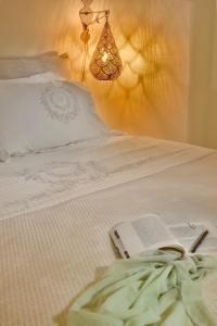 a bedroom with a bed with a book and a lamp at THE A COLLECTION by K&K in Oia