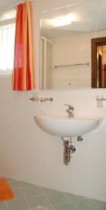 ein Badezimmer mit einem weißen Waschbecken und einem Spiegel in der Unterkunft Ferienwohungen Wassertheurer in Sankt Kanzian am Klopeiner See