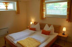 Schlafzimmer mit einem Bett mit weißer Bettwäsche und orangefarbenen Kissen in der Unterkunft Ferienwohungen Wassertheurer in Sankt Kanzian am Klopeiner See