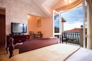 a bedroom with a bed and a tv and a balcony at Apartments Villa Paradise in Kaštela
