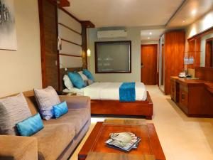 ein Wohnzimmer mit einem Bett und einem Sofa in der Unterkunft Fairway Hotel & Spa in Kampala