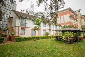 a yard with tables and umbrellas in front of a building at ACK Guest House Nairobi in Nairobi
