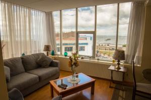 sala de estar con sofá y vistas al océano en Departamentos Los Ganaderos, en Punta Arenas