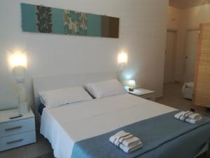 una camera da letto con un grande letto bianco con asciugamani di Casa Dolce Puglia Casa Vacanza a Castellana Grotte