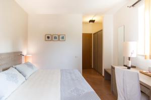 a white bedroom with a bed and a desk at Hotel Aquadulci in Chia