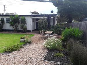 a backyard with a garden with chairs and plants at Bay Bell Cottage in Saint Leonards