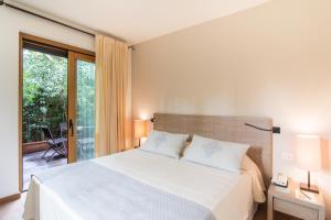 a bedroom with a large bed and a balcony at Hotel Aquadulci in Chia