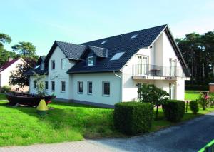 una casa blanca con un barco en el patio en Appartementhaus Zur Schaabe, en Glowe