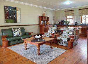 uma sala de estar com uma mesa de centro e cadeiras em Berluda Farmhouse and Cottages em Oudtshoorn