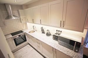 a kitchen with white cabinets and a sink at Hunters Walk - Luxury Central Chester Apartment - Free Parking in Chester