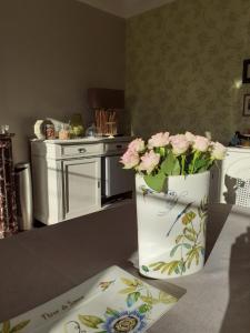 un vaso pieno di fiori rosa seduto su un bancone della cucina di Fleur De Senon a Senon