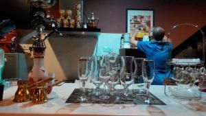 a man standing behind a table with glasses on it at Zeala Asmara Motel in Kuah
