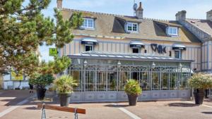 un bâtiment avec un banc devant lui dans l'établissement Le Manoir d'à Côté, à Courseulles-sur-Mer