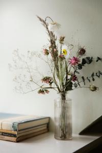 a vase of flowers sitting on a table next to a book at Helenekilde Badehotel in Tisvildeleje