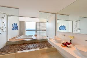 a bathroom with a sink, mirror, and bathtub at Kempinski Hotel Aqaba in Aqaba