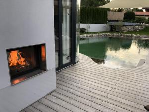 a fireplace on the side of a house next to a swimming pool at Das Poolhaus in Rottau